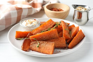 Pieces of tasty baked sweet potato with microgreens served on white wooden table, closeup