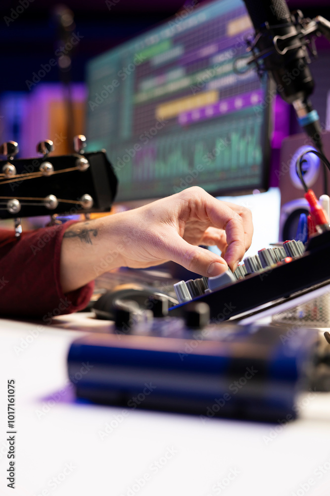 Poster music producer twisting pre amp knobs on mixing console to edit audio recordings in home studio, wor