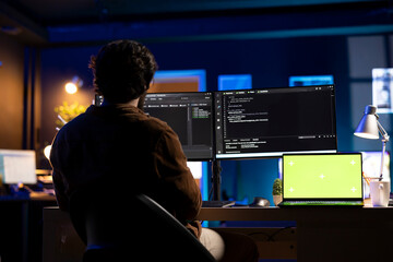 Programmer using green screen laptop to implement security measures, protecting company systems and...