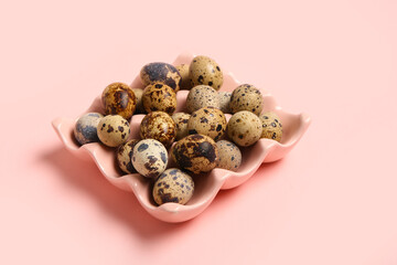 Holder with fresh quail eggs on pink background