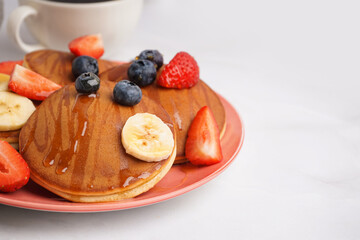 Tasty pancakes with blueberries and banana on white background