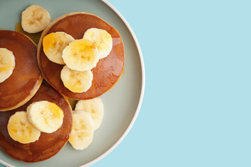 Tasty pancakes with honey and banana on blue background