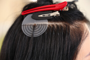 Young woman getting hair extensions in beauty salon, closeup