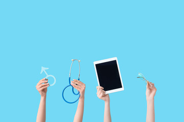Female hands with male sign, stethoscope, tablet computer and eyeglasses on blue background....