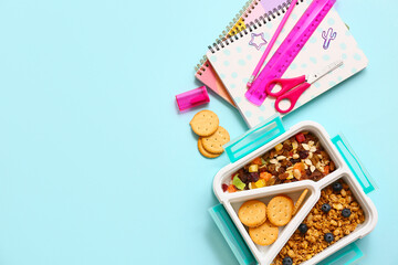 Lunch box with tasty food and school stationery on blue background