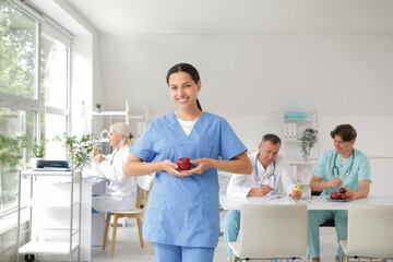 Fototapeta premium Young female doctor with apple in clinic