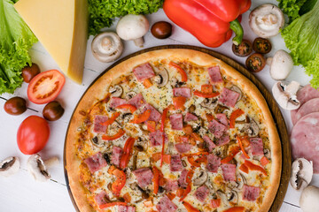 High angle view of homemade pizza on wooden table surrounded by vegetables, mushrooms and cheese