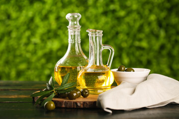 Decanters of fresh olive oil on black wooden table outdoors