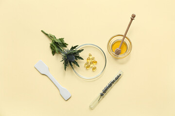 Laboratory glassware with plants and ingredients for preparing natural cosmetics on yellow background