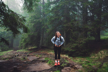 Obraz premium A person running through a misty forest, navigating over tree roots and muddy ground. The scene captures the essence of outdoor adventure and fitness, surrounded by lush greenery and fog.