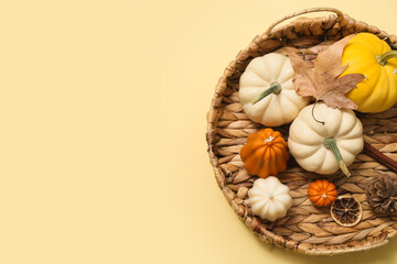 Wicker tray with ripe pumpkins and autumn candles on color background
