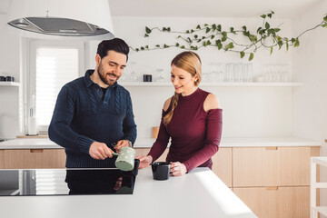 Obraz premium The couple go about their daily chores in the apartment. The couple talks in the kitchen, sits on the sofa, at the dining table.