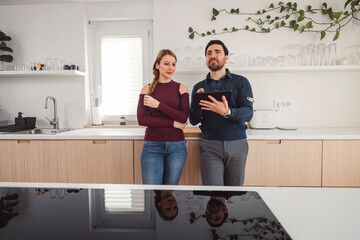 The couple go about their daily chores in the apartment. The couple talks in the kitchen, sits on the sofa, at the dining table.