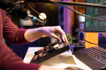 Audio engineer twisting pre amp knobs to edit tunes in post production, working with stereo...