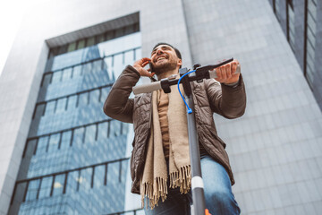 A man rides an electric scooter around the city in front of the glass building where he works