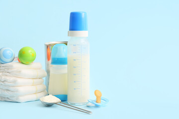 Bottles with baby milk formula, diapers, rattle and pacifier on color background