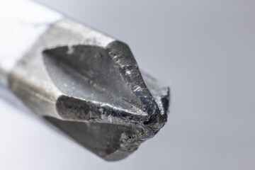 A close-up of a worn, metallic phillips head screwdriver with a flattened tip and visible wear...