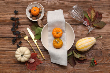 Autumn table setting with pumpkins and fallen leaves on wooden background