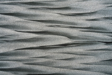 Background: nature's art graphic resource. A monochrome scene of black volcanic and golden sands mixed into diamond shapes by the sea on a beach at Little Wanganui, New Zealand