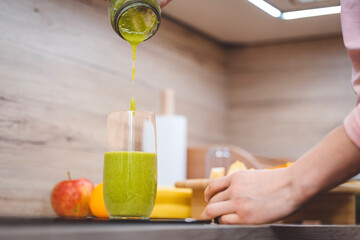 Healthy eating lifestyle concept photo of young woman preparing drink with fruit and vegetables at home in kitchen.