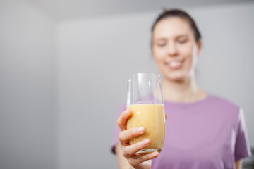 A young woman drinks a vegetable and fruit smoothie in her living room and doing yoga on yoga mat.