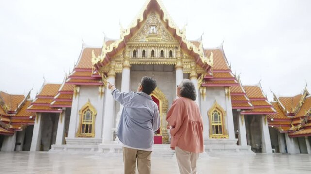 Group of Asian senior woman tourist enjoy and fun outdoor lifestyle travel Bangkok city, Thailand on summer holiday vacation. Elderly retired women looking at beautiful architecture of buddha temple.