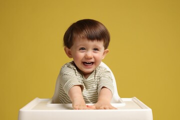 Cute little kid sitting in high chair on yellow background