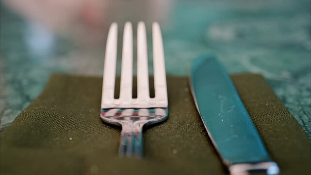 Close up of a fork and a table knife on a green napkin