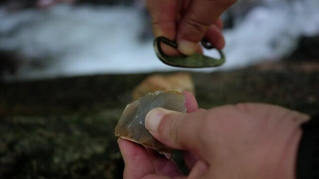 slow motion striking a piece of high-carbon steel against a sharp edge of flint stone.