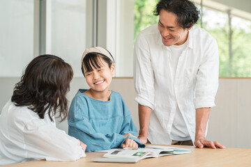 娘の勉強を見ている母親と父親（ファミリー・宿題・受験・受験勉強）
