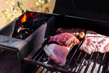 Making a barbecue with a portbale grill in the balcony of apartment. Traditional roast beef of Argentina. Asado.