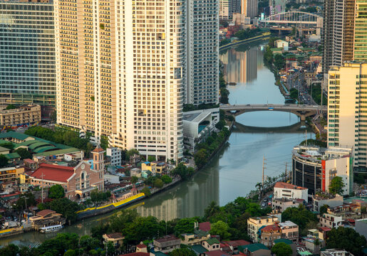 Catholic Church building,dwarfed by surrounding skyscrapers,lining the Pasig River in downtown Manila,Luzon,the Philippines