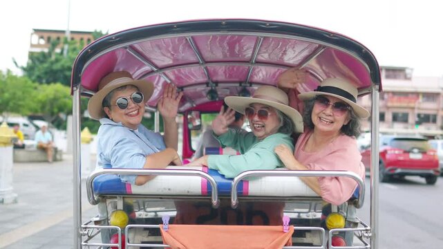 Group of Asian senior woman tourist enjoy outdoor lifestyle travel Bangkok city, Thailand on summer holiday vacation. Elderly women travel Wat Phra Kaew Temple by three wheeled vehicles Tuk Tuk taxi.