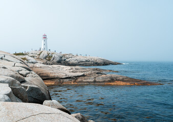 Tourists explore around Peggy's Cove Lighthouse as the fog lifts
