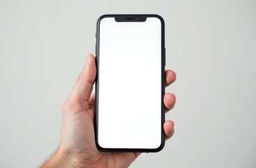 Hand holding a smartphone with a blank screen against a plain background in a well-lit setting