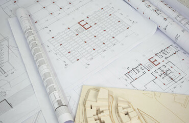 Architectural and structural drawings background. Rolled up plans with scale architectural model