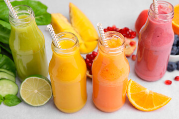 Glass bottles of tasty smoothies and different products on white table