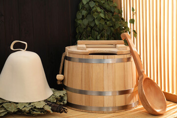 Sauna equipment. Bucket, ladle, felt wool hat and whisks on bamboo bench indoors