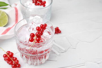 Refreshing water with red currants in glass on light table, closeup. Space for text