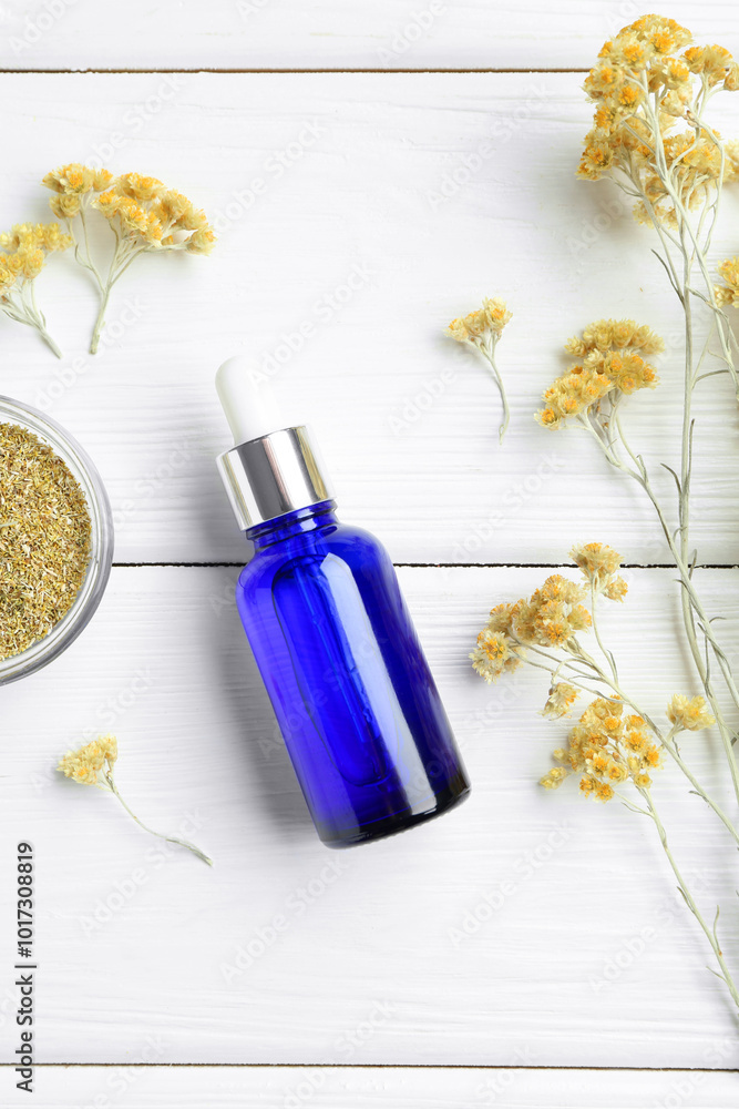 Wall mural Bottle of tincture and helichrysum flowers on white wooden table, flat lay