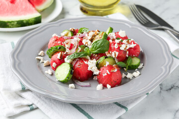 Delicious watermelon salad with feta cheese, vegetables and spices served on white marble table, closeup
