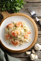 Delicious pasta with shrimps, green onions, lime, garlic and parsley on wooden table, flat lay