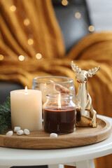 Burning candles, fir branches and decorative deer on coffee table indoors. Christmas atmosphere