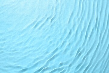 Obraz premium Rippled surface of clear water on light blue background, top view