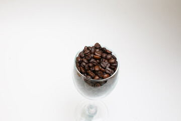 Coffee beans in wine glass on white background