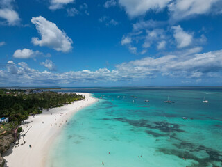 Aerial view of Nungwi Beach, Zanzibar, showing white sand, turquoise waters, boats in the ocean, and palm tree-lined coastline. Captures the geography of a popular tourist destination in East Africa.