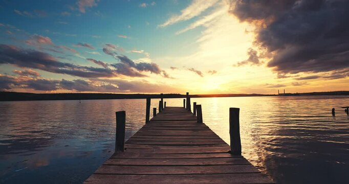 Colorful tropical sunset over wooden fishing pier and ripple sea water video