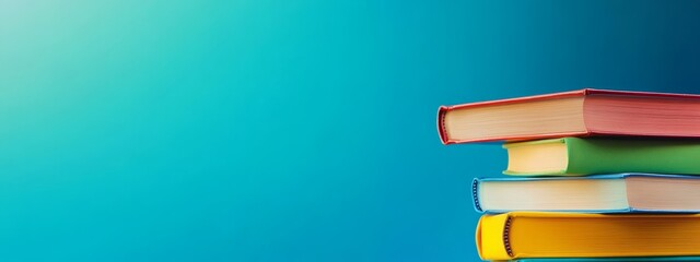 Fototapeta premium Stack of colorful books on a blue background.