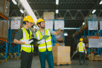 Three warehouse workers using a digital tablet while recording inventory. Logistics employees...