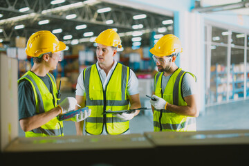 Three warehouse workers using a digital tablet while recording inventory. Logistics employees...
